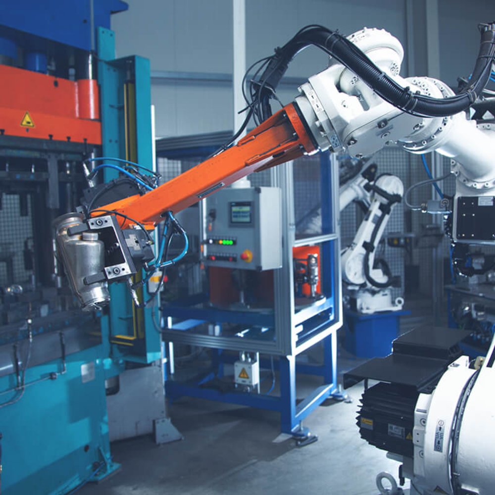 Ein Roboterarm der ein Werkstück aus Metall hält.