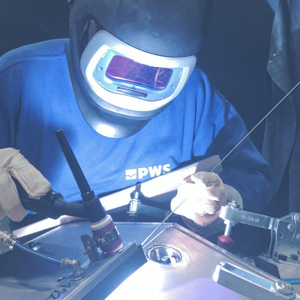 Man with a welding mask welding.